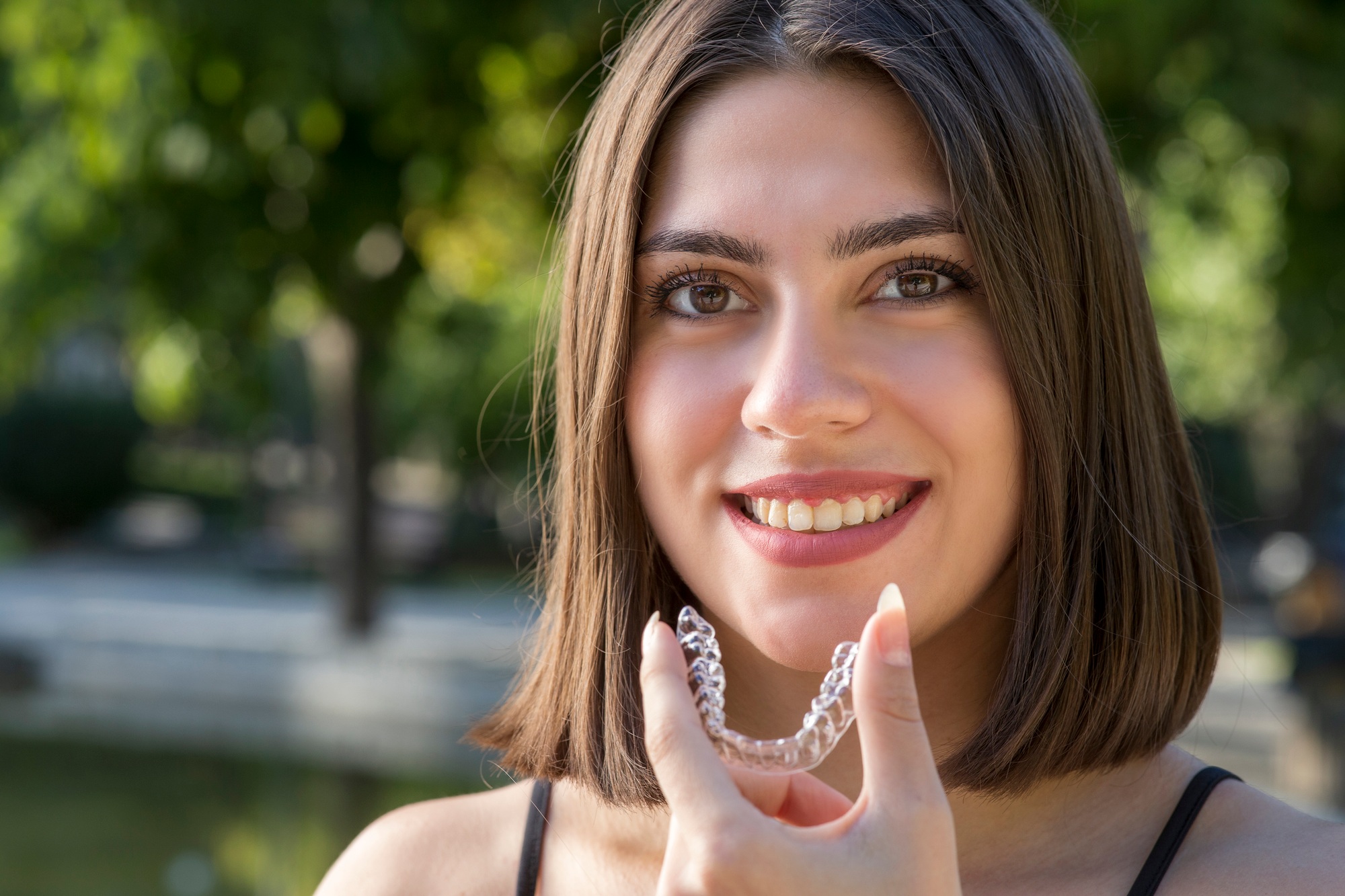 Beautiful smiling Turkish woman is holding an invisalign bracer