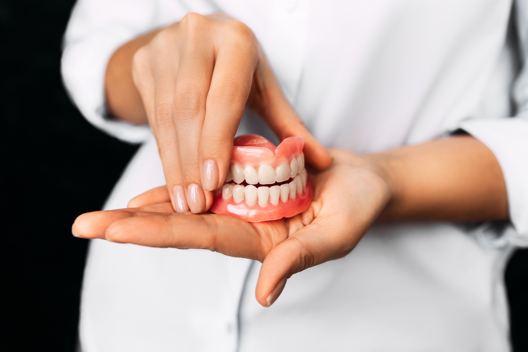The dentist is holding dentures in his hands. Dental prosthesis in the hands of the doctor