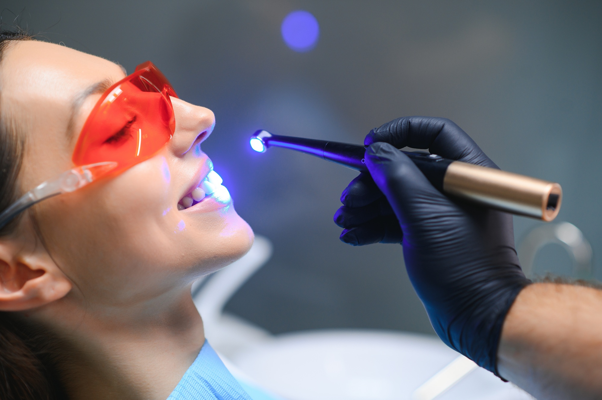 Young woman getting dental filling drying procedure with curing UV light at dental clinic